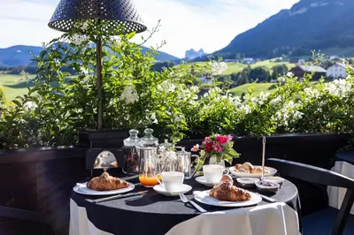 a table with food on it with a view of mountains at Hotel MAYR in Castelrotto