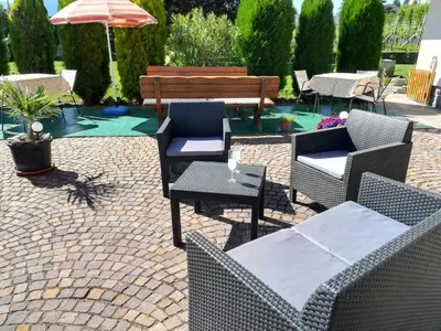 a patio with chairs and a bench and an umbrella at Gästehaus Thaler in Caldaro