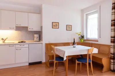 a kitchen with a white table and chairs and a kitchen with white cabinets at Gästehaus Thaler in Caldaro