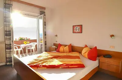 a bedroom with a large bed with a balcony at Gästehaus Thaler in Caldaro