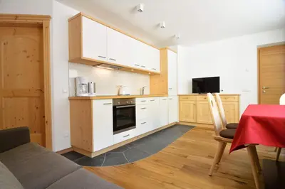 a kitchen with white cabinets and a table with chairs at Cesa Setil in Ortisei