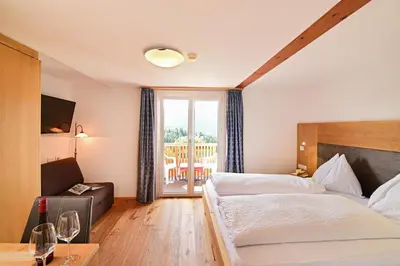 a hotel room with two beds and a balcony at Hotel Tirolerhof in Terento
