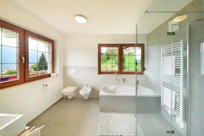 a bathroom with a tub and a toilet and a sink at Hotel Tirolerhof in Terento
