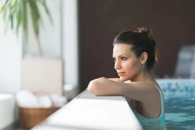 a woman sitting in a swimming pool at Hotel Tirolerhof in Terento