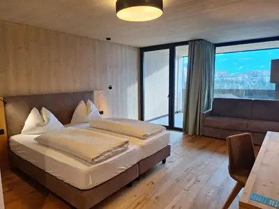 a bedroom with a bed and a couch in a room at Hotel Tirolerhof in Terento