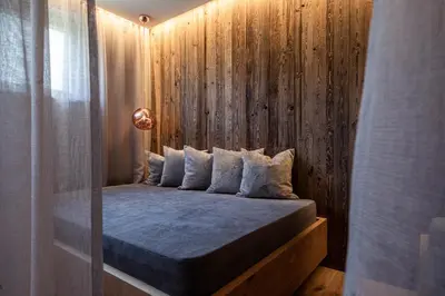 a bedroom with a bed with a wooden wall at B&B Boutiquehotel Clara in Brunico