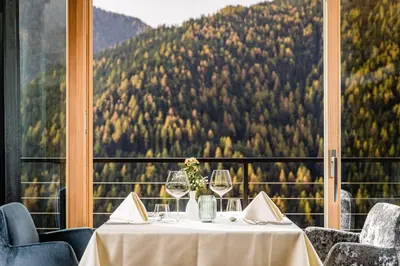 a table with wine glasses in front of a window at Bella Vista Hotel Emma in San Vigilio Di Marebbe
