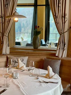 a table with wine glasses and a window at Bella Vista Hotel Emma in San Vigilio Di Marebbe