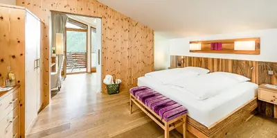 a bedroom with a large bed and a wooden wall at Bella Vista Hotel Emma in San Vigilio Di Marebbe
