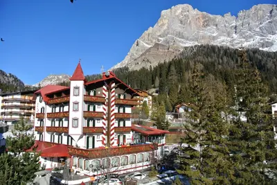 a large building with a mountain in the background at Hotel Regina in San Martino di Castrozza