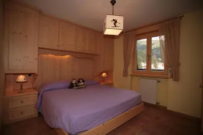 two teddy bears sitting on a bed in a bedroom at Appartamenti Cercenà Deluxe in Canazei