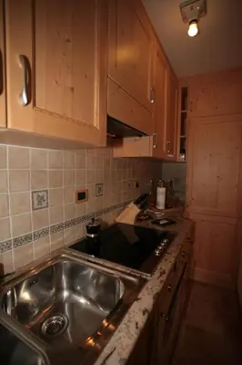 a kitchen with a stainless steel sink and wooden cabinets at Appartamenti Cercenà Deluxe in Canazei
