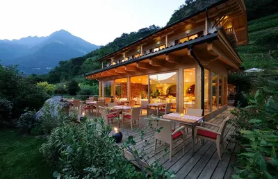 a house with tables and chairs on a deck at Hotel Garni Partaneshof in Merano