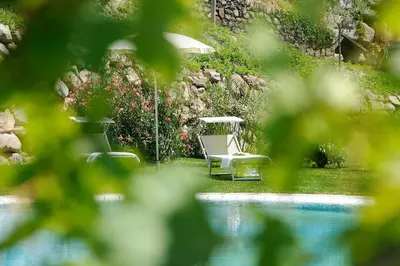 a pool with two chairs and a table and an umbrella at Hotel Garni Partaneshof in Merano