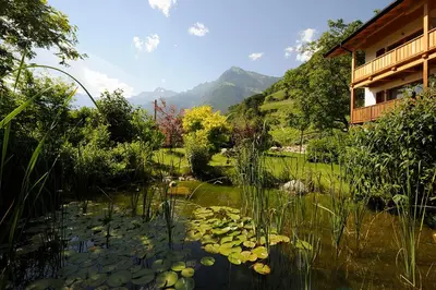 a pond with lily pads in front of a house at Hotel Garni Partaneshof in Merano