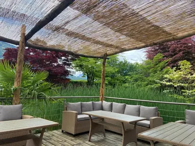 a patio with tables and chairs on a deck at Hotel Garni Partaneshof in Merano
