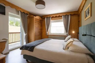 a bedroom with two beds and a chair in it at Hotel Aurora in Canazei