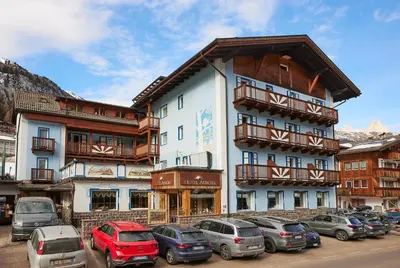 a large building with cars parked in a parking lot at Hotel Aurora in Canazei
