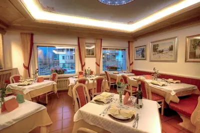 a dining room with an archway and tables and chairs at Hotel Aurora in Canazei