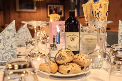 a table with a bottle of wine and a plate of bread at Hotel Aurora in Canazei