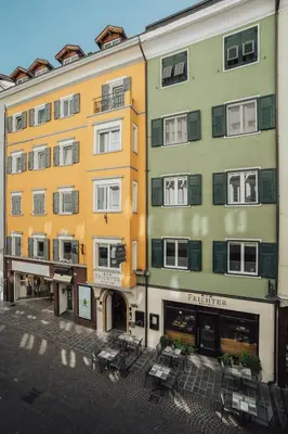 a bedroom with a large bed and a mirror at Feichter Hotel & Living in Bolzano