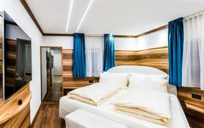 a bedroom with a white bed with blue curtains at Apartments Villa Venezia Luxury in Ortisei