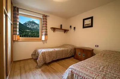 a bedroom with two beds and a window with a mountain view at Casa Fam.Barbolini in Tesero