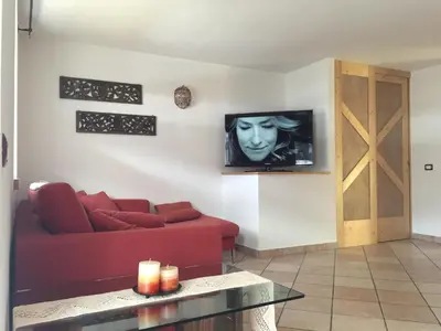 a living room with a red couch and a tv at Casa Fam.Barbolini in Tesero