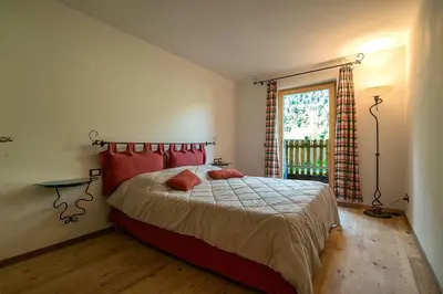 a bedroom with a bed with red pillows and a window at Casa Fam.Barbolini in Tesero