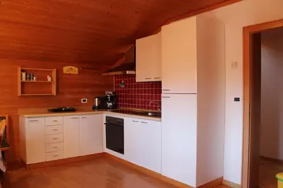 a kitchen with white cabinets and a wooden ceiling at Ciasa Nea in Longega