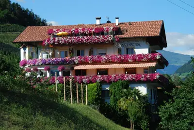 a building with flowers on the side of it at Pension Weinberg in Rifiano