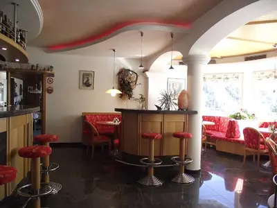 a bar in a restaurant with red stools at Pension Weinberg in Rifiano