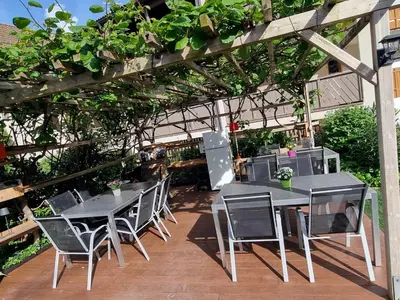 a table and chairs under a pergola with plants at Hofer Hof in Andrian