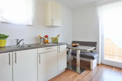 a white kitchen with a sink and a table at Appartments mir.es in Tirolo