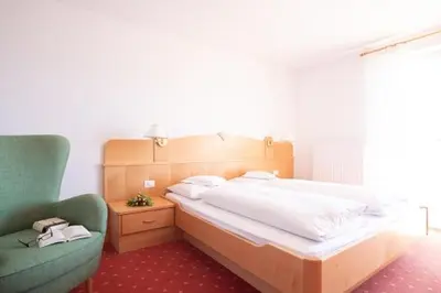 a bedroom with a large bed and a green chair at Appartments mir.es in Tirolo