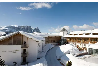 a building covered in snow with mountains in the background at Seiser Alm Urthaler in Alpe di Siusi