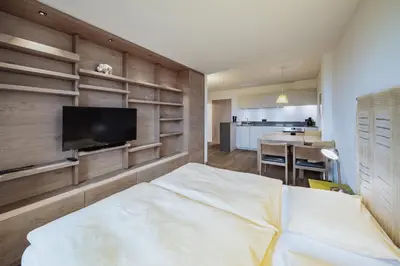 a room with a bed and a tv and shelves at Seiser Alm Plaza in Alpe di Siusi