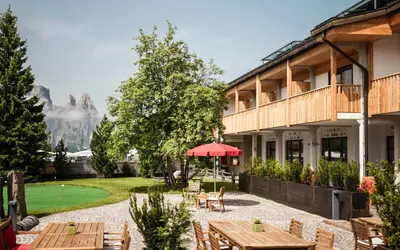 a patio with tables and chairs and a building at Seiser Alm Plaza in Alpe di Siusi