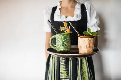 a woman holding a tray with two cups and plants at Romantik Hotel Turm in Fiè