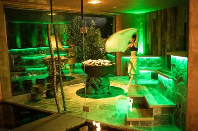 a woman walking in a room with green lights at Romantik Hotel Turm in Fiè