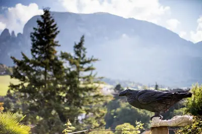 a bird sitting on top of a fence with a mountain at Romantik Hotel Turm in Fiè