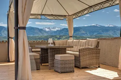 a patio with wicker furniture and a view of mountains at Pension Irma in Caldaro