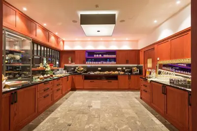 a large kitchen with wooden cabinets and a bar at Alpin Natur Hotel Brückele in Braies