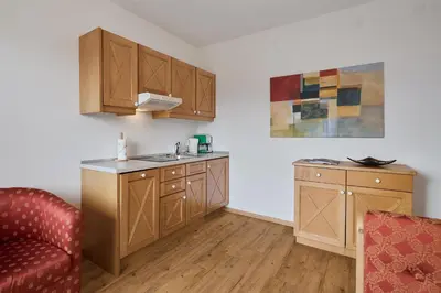 a kitchen with wooden cabinets and a red couch at Apartments in Kaltern, Panorama-Terrasse mit Bergblick nahe Zentrum in Caldaro