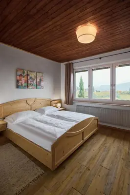 a bedroom with a large wooden bed and windows at Apartments in Kaltern, Panorama-Terrasse mit Bergblick nahe Zentrum in Caldaro