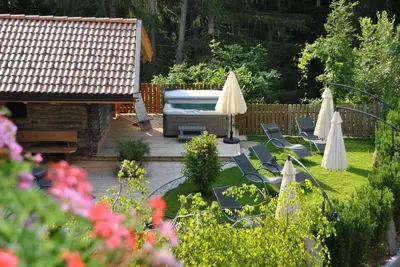 a garden with umbrellas and chairs and a grill at Hotel Wieslhof in Collepietra