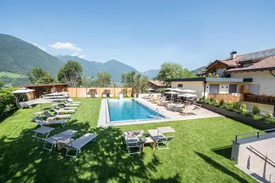 an image of a swimming pool with chairs and a resort at Hotel Kranebitt B&B in Bressanone