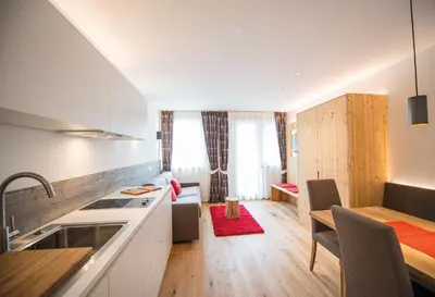 a kitchen and a living room with a table at Hotel Kranebitt B&B in Bressanone