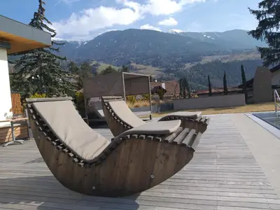 a wooden bench sitting on a patio with mountains in the background at Hotel Kranebitt B&B in Bressanone