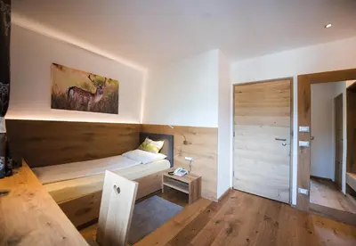a bedroom with a bed with a wooden wall at Hotel Kranebitt B&B in Bressanone